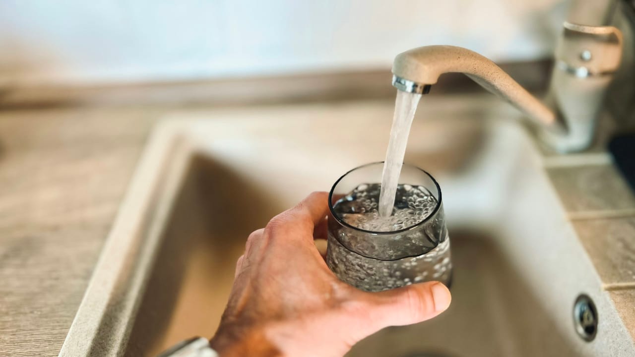 A glass being filled with tap water at a kitchen sink